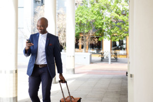 51498361 - portrait of businessman traveling with a bag and mobile phone